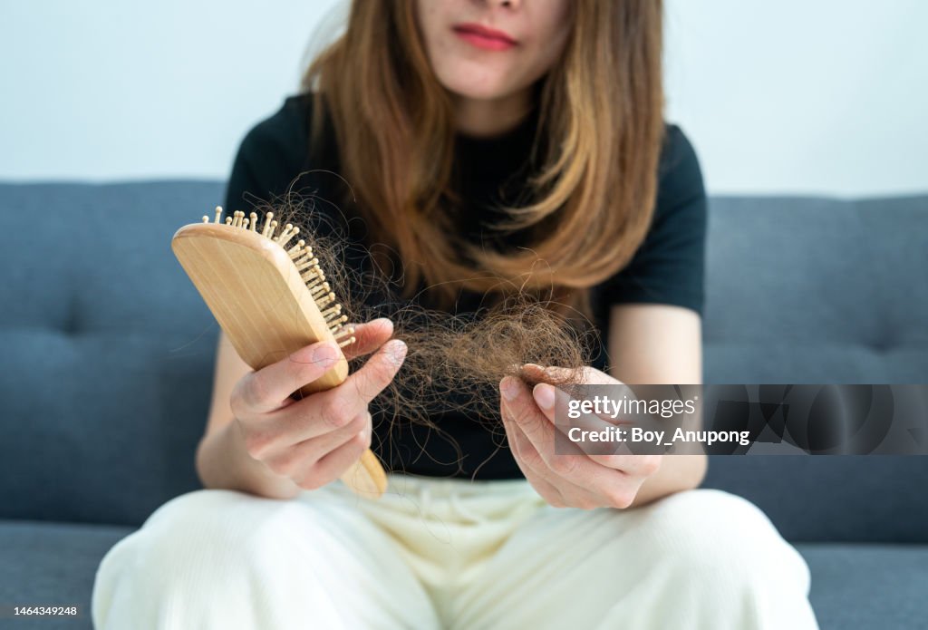 Cropped shot of worried woman holding comb with hair loss after brushing her hair.