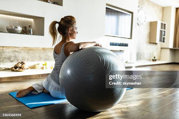 athletische frau, die sich zu hause auf fitnessball ausruht. - pilates ball man stock-fotos und bilder