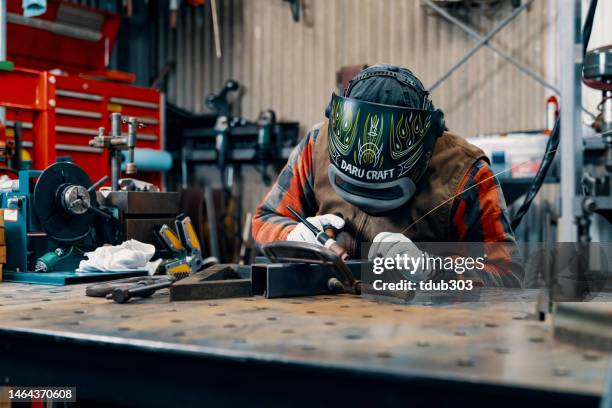 mid adult man welding in his metal fabrication workshop - welding mask stock pictures, royalty-free photos & images