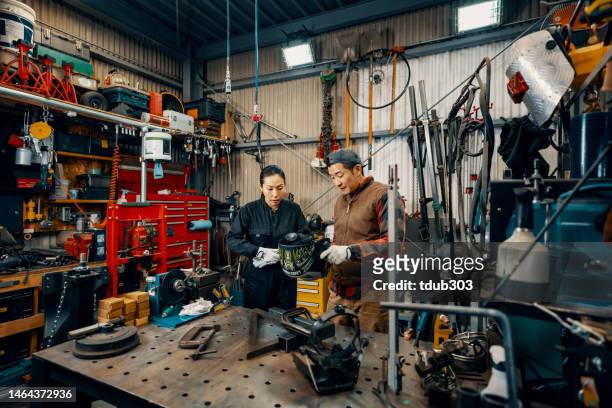 Mid adult man teaching a female employee how to weld in a metal fabrication workshop