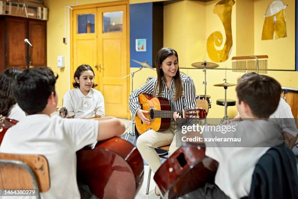escolares tocando guitarras acústicas con profesor - fraternity band fotografías e imágenes de stock