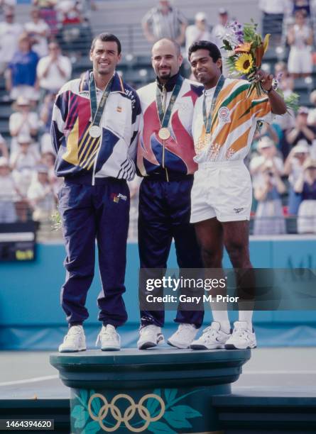Gold medalist Andre Agassi from the United States celebrates on the winners podium with silver medalist Sergi Bruguera of Spain and bronze medalist...