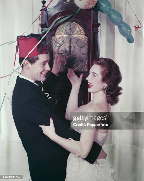 Posed studio portrait of English model and actress Shirley Anne Field and a male model embracing as they celebrate New Year's Eve in front of a...