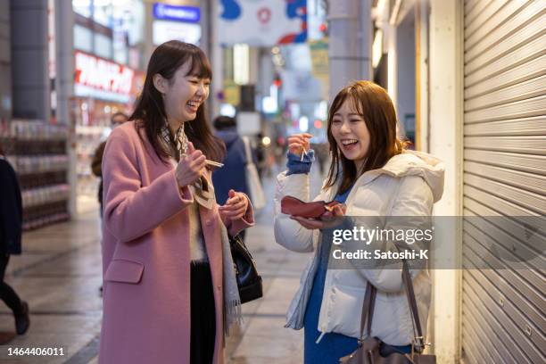 happy female friends talking together and eating takoyaki in shopping street - takoyaki stock pictures, royalty-free photos & images