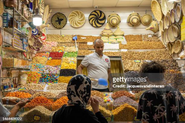 a male vendor stands in his market stall in the medina (old, historic shopping center) in marrakech, morocco - marrakech spice stock pictures, royalty-free photos & images