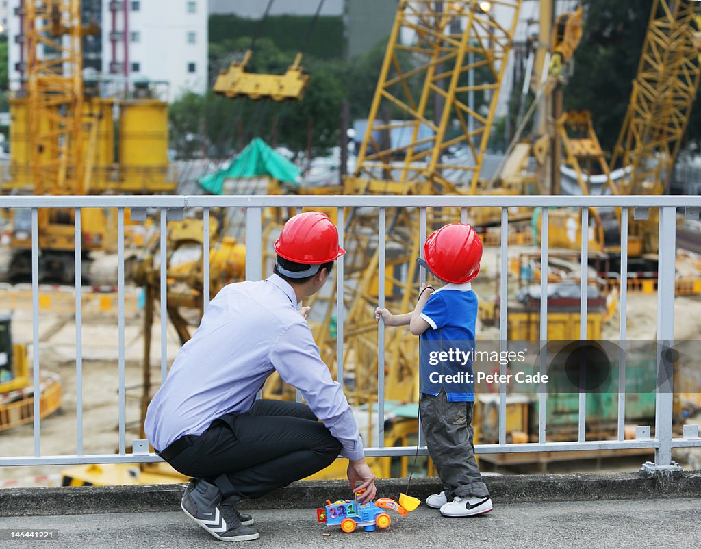Father looking at building site with young son