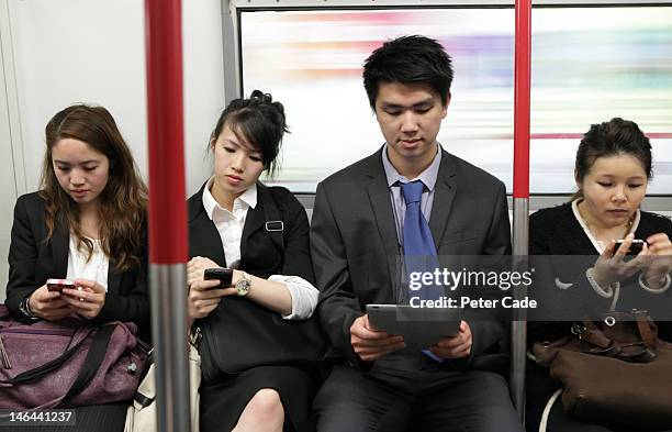 people sat on train looking at phoes and computers - hong kong transport stock-fotos und bilder