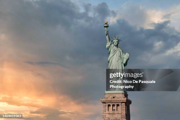 sunset over the statue of liberty in new york city, usa - statue of liberty new york city - fotografias e filmes do acervo
