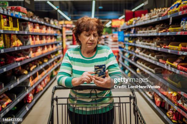 senior woman checking shopping list on smartphone - dolours price stock pictures, royalty-free photos & images