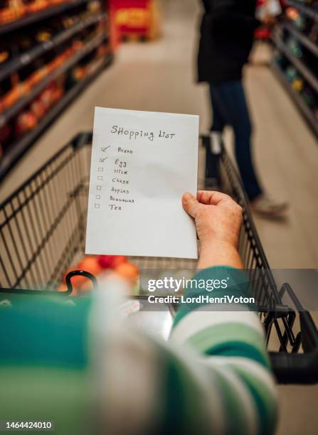 woman with shopping list in grocery store - shopping list stock pictures, royalty-free photos & images