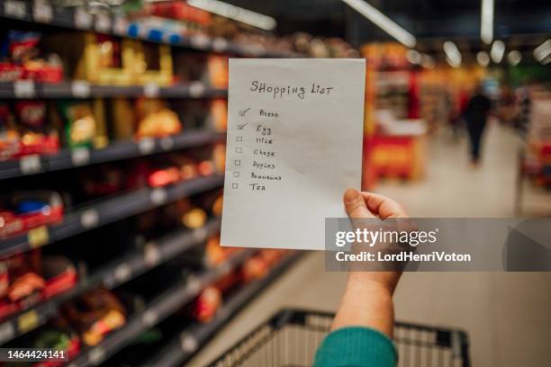 woman with shopping list in grocery store - shopping list stock pictures, royalty-free photos & images