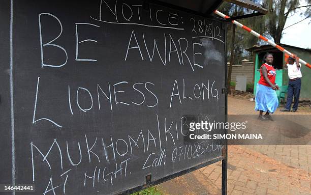 Kenyan woman walks past a notice put up on June 8, 2012 outside the main entrance of residential houses in Karen, Nairobi's upmarket area. The notice...