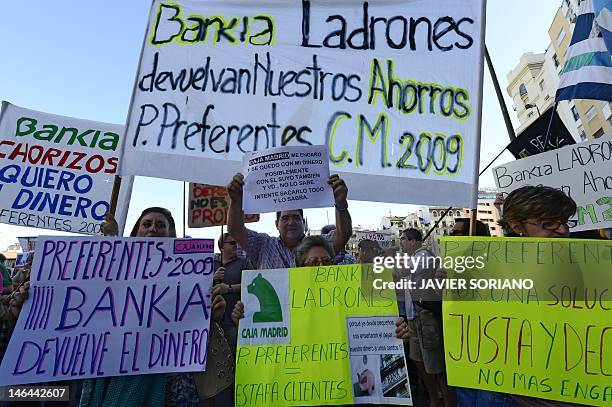 People hold placards reading "Bankia, thieves, gives us our savings back" during a demonstration against fraud on June 16, 2012 in Madrid. Spain's...