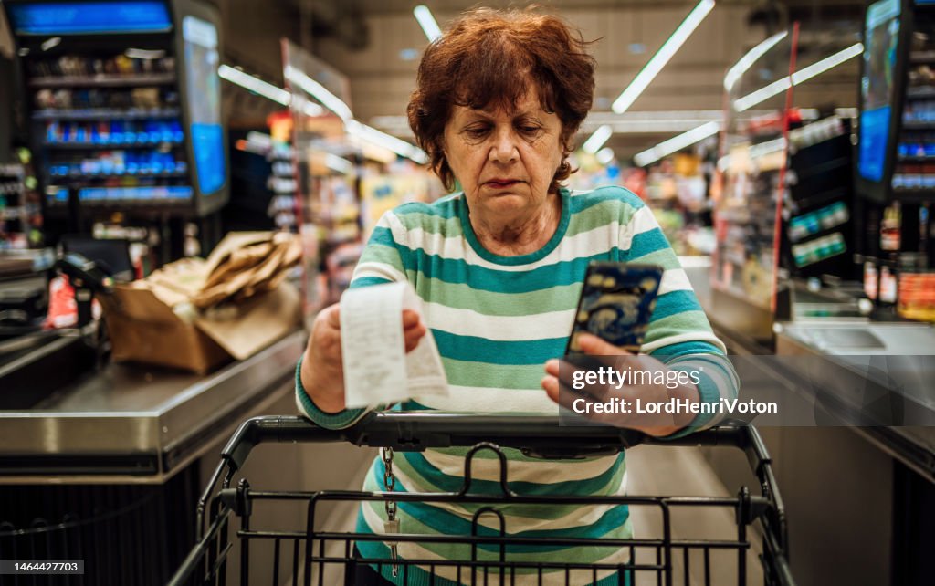 Senior woman checking bill after shopping at the supermarket