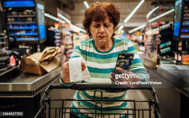 senior woman checking bill after shopping at the supermarket - expense receipts stock pictures, royalty-free photos & images