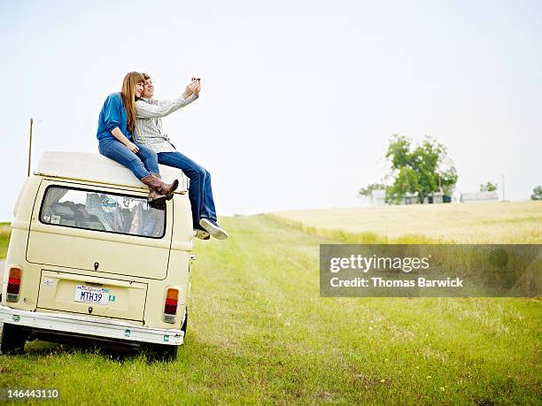 couple sitting on top of van taking photo - boyfriend jeans stock pictures, royalty-free photos & images