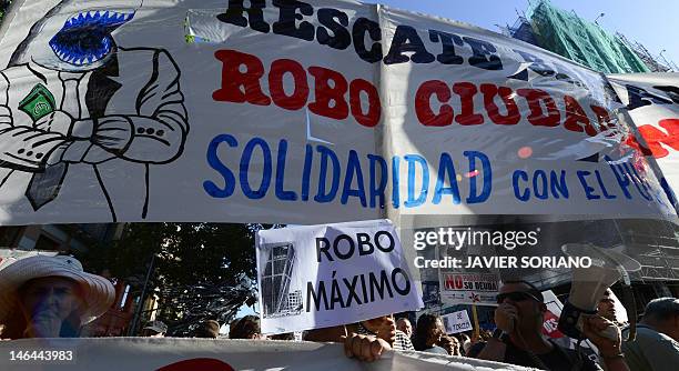 People holding a banner reading "Bank bailout: a citizen robbery" attend a demonstration against bank fraud on June 16, 2012 in Madrid. Spain's...