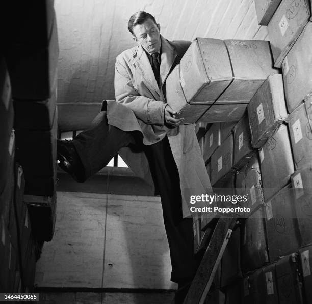 Mr R W Collie, Assistant Keeper of Records, lifts up a cardboard storage box containing the larger volume Great Domesday book and smaller volume...