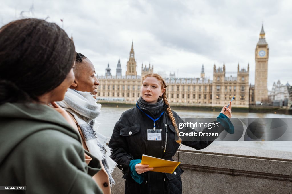 Junge Touristen in London, gefolgt von einem privaten Reiseleiter, der ihnen das Parlament und den Big Ben zeigt