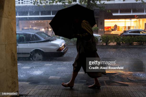 Person holding an umbrella walks during a sudden rain storm on February 09, 2023 in Sydney, Australia. On July 6, 2022 the Australian government...