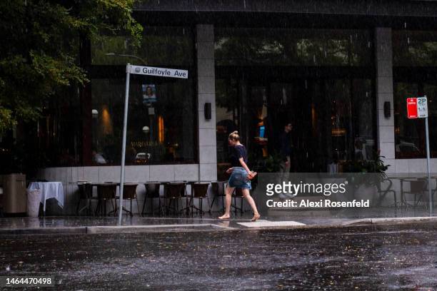 Person walks barefoot during a sudden rain storm on February 09, 2023 in Sydney, Australia. On July 6, 2022 the Australian government lifted all...
