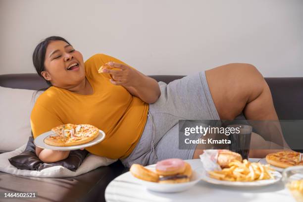 Plus Size Woman Laying Down On Sofa And Eating Junk Food High-Res