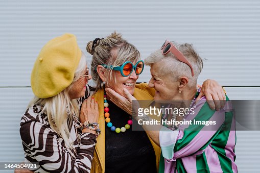 Portrait of happy three senior friends in colourful clothes.