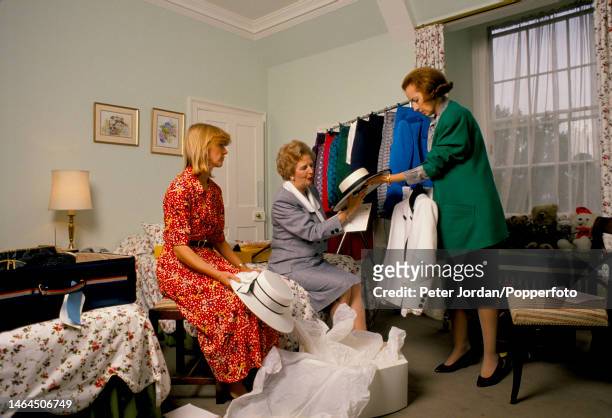 Conservative Party politician and Prime Minister of the United Kingdom Margaret Thatcher , with the help of two assistants, chooses an outfit and hat...