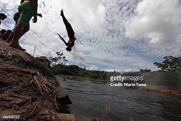Man flips into a stream leading to the Xingu River near the area where the Belo Monte dam complex is under construction in the Amazon basin on June...