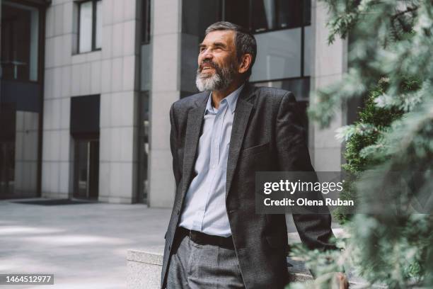 happy mature business man standing near conifer trees. - green blazer stockfoto's en -beelden