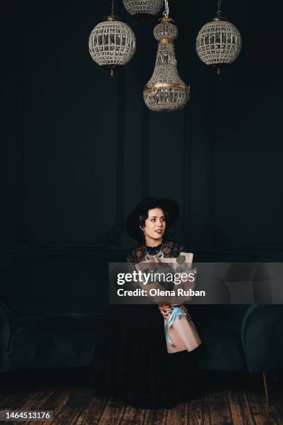 young woman in black dress with blue flowers under luxury chandeliers. - pendant light stock pictures, royalty-free photos & images