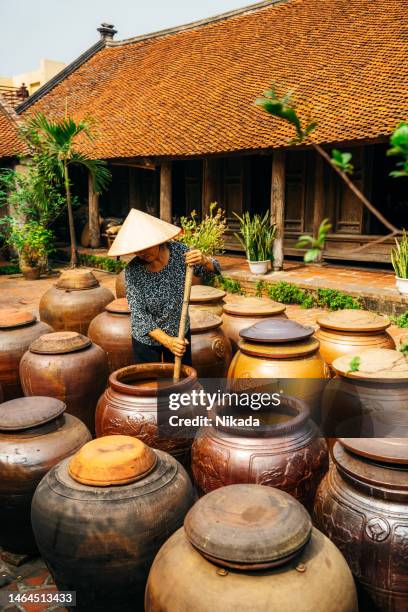 vietnamese woman stirring soy sauce in huge clay pod in vietnam - jäst bildbanksfoton och bilder