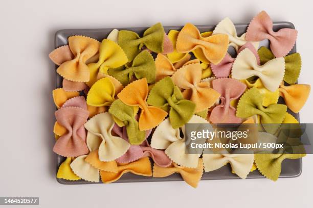 colored raw farfalle pasta on a gray tray,roman,romania - farfalle stock-fotos und bilder