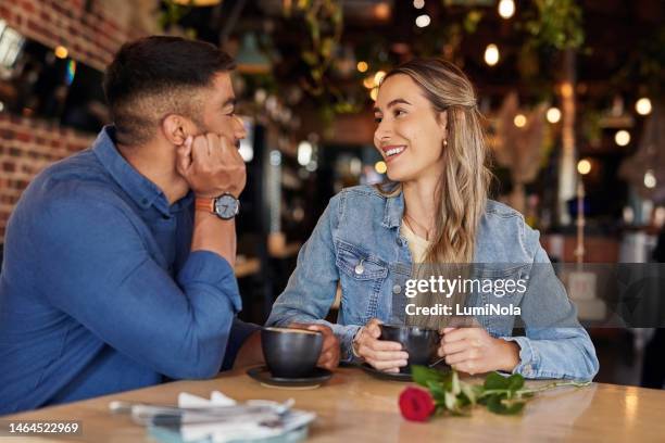 coffee shop, date and couple of friends with rose for valentines day, anniversary or love in restaurant bokeh. happy diversity people or woman with love partner at cafe at night for social talking - daten stockfoto's en -beelden