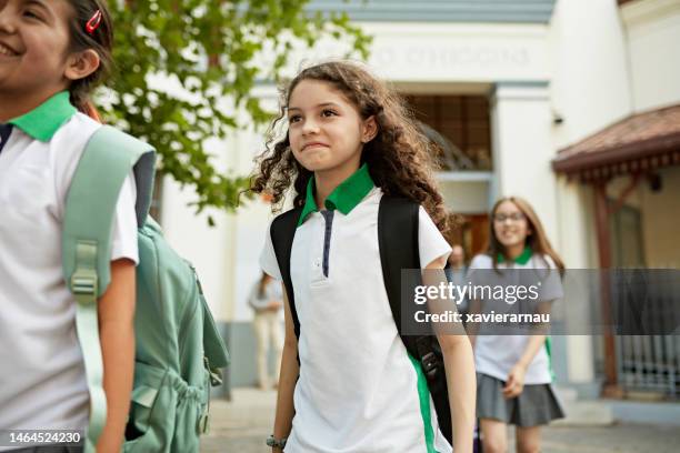 happy female students leaving school at end of day - girl in school uniform stock pictures, royalty-free photos & images