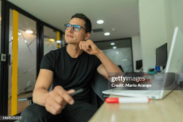 latino man is inside the office of the company he works for, with a laptop organizing pending work - pending stock pictures, royalty-free photos & images