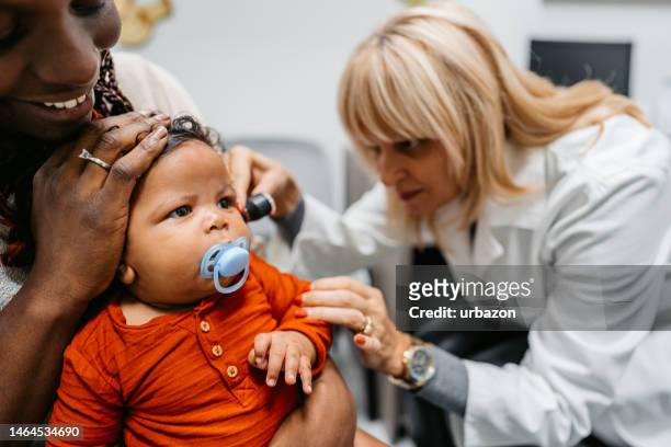 young female pediatrician examining a newborn baby boy - otoscope bildbanksfoton och bilder