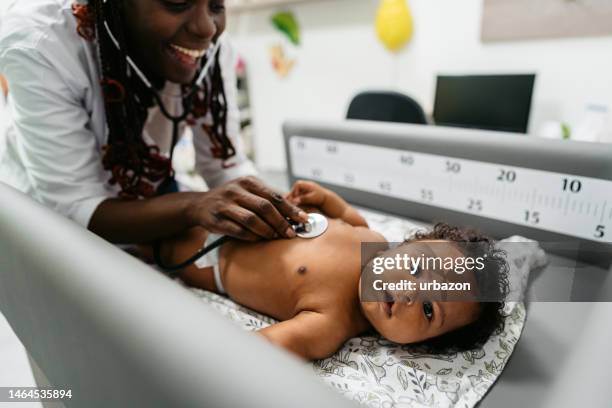 female pediatrician auscultating a newborn baby - kinderarts stockfoto's en -beelden