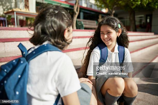 Grinning schoolgirl taking a break outdoors with classmate