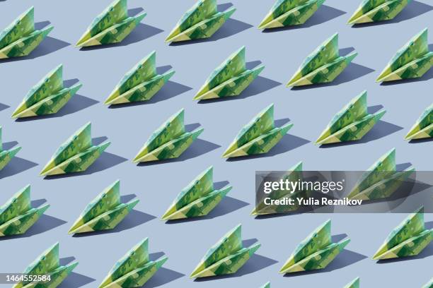 repeated 100 euro banknotes in shape of airplanes on the blue background - inflation euro stock-fotos und bilder