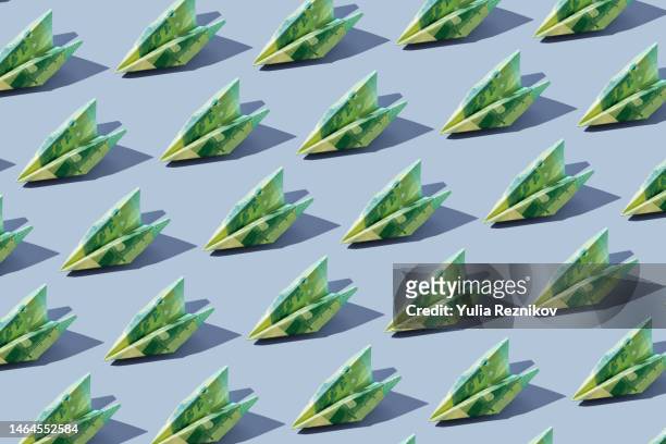 repeated 100 euro banknotes in shape of airplanes on the blue background - inflation euro stock pictures, royalty-free photos & images
