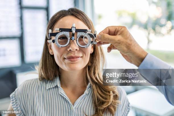 nahaufnahme einer jungen frau, die bei optiker eine brillenbrille wählt - lens eye stock-fotos und bilder