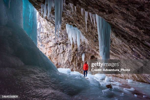 wanderer erkunden gefrorene eishöhle - höhlenforscher stock-fotos und bilder