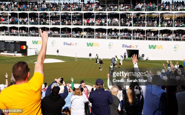 Fans cheer as Tony Finau of the United States waves after putting on the 16th green during the first round of the WM Phoenix Open at TPC Scottsdale...