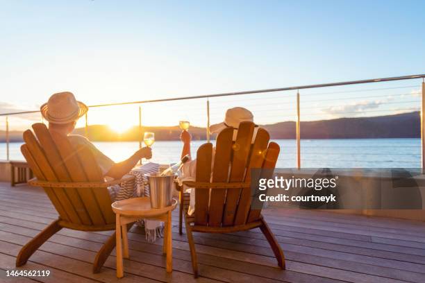 paar entspannt sich und trinkt wein auf liegestühlen - beach deck chairs stock-fotos und bilder