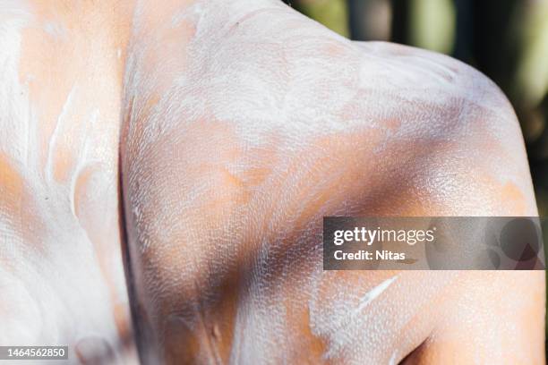 back of a young woman with sun tan. hand spreads the lotion to protect her from the sun. skincare concept - applying cream stock pictures, royalty-free photos & images