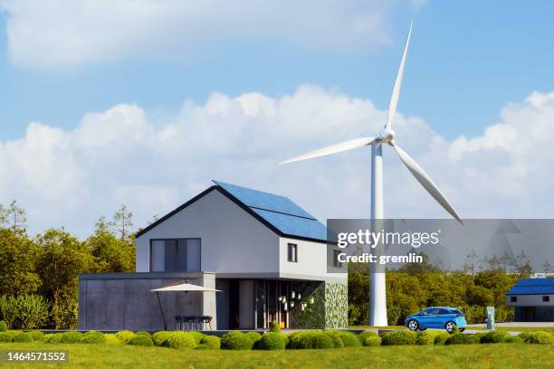 casa moderna con paneles solares fotovoltaicos en el techo y turbina eólica - casa molina fotografías e imágenes de stock