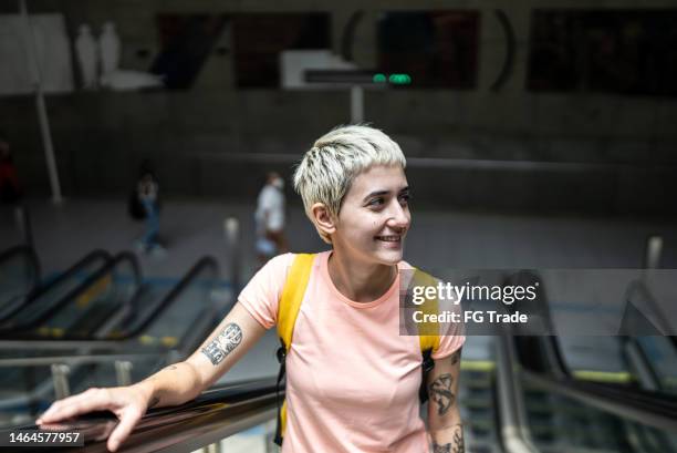 jeune femme sur l’escalator qui monte et regarde autour de lui dans la station de métro - coloration photos et images de collection