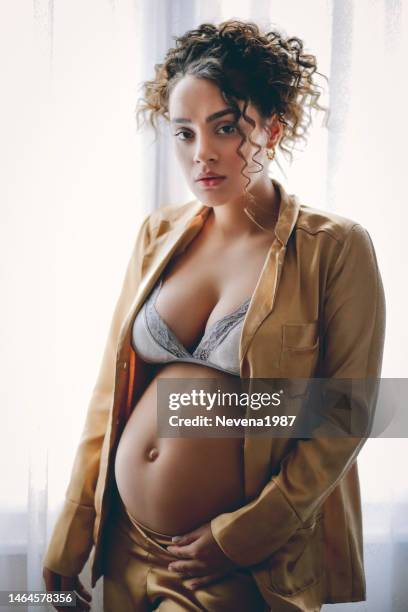 sensual pregnant woman standing beside the window at hom - hom stock pictures, royalty-free photos & images