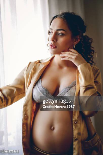 sensual pregnant woman standing beside the window at hom - hom stock pictures, royalty-free photos & images